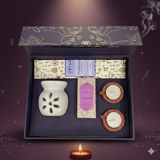 A gift set with a white ceramic diffuser, candles, and boxes on a dark background.